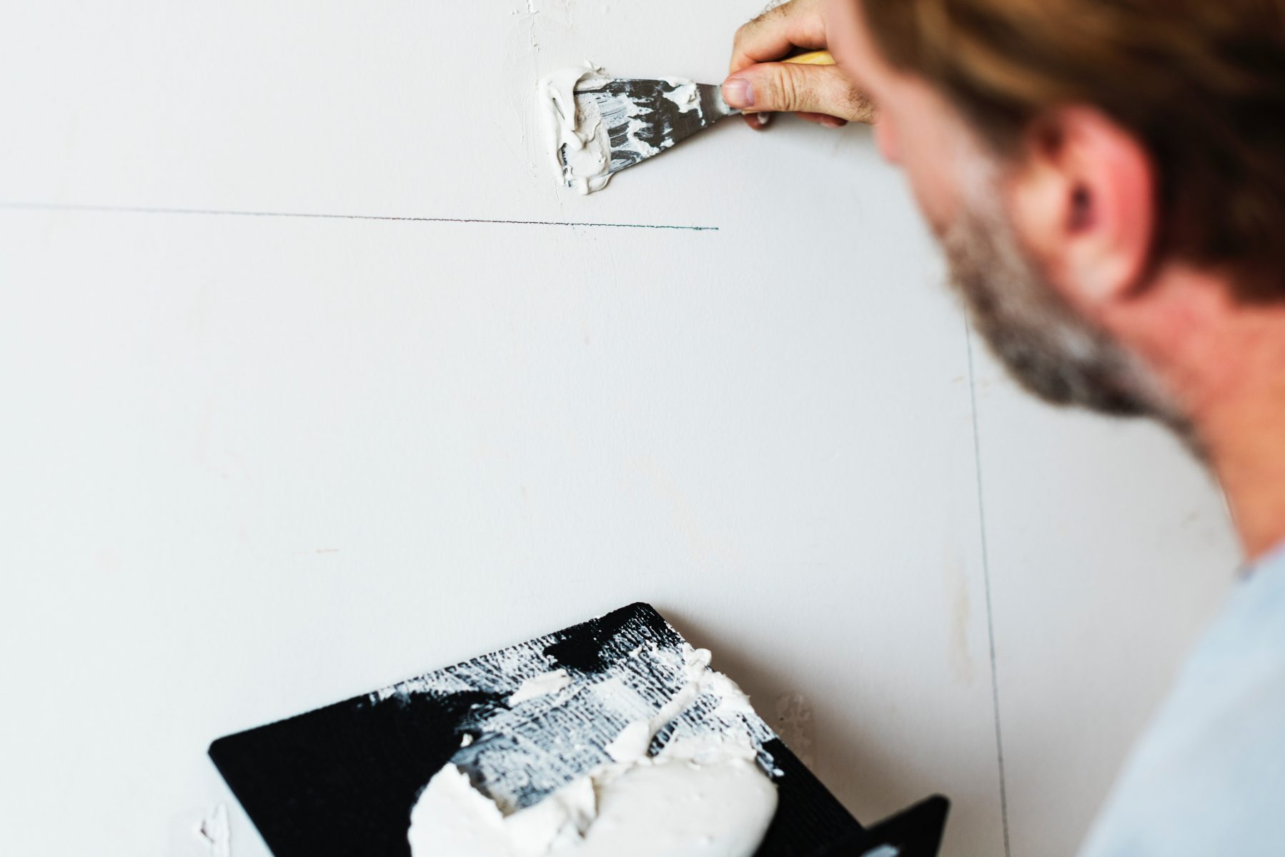 photo of a home renovation specialist applying applying putty on the wall - home renovation tips